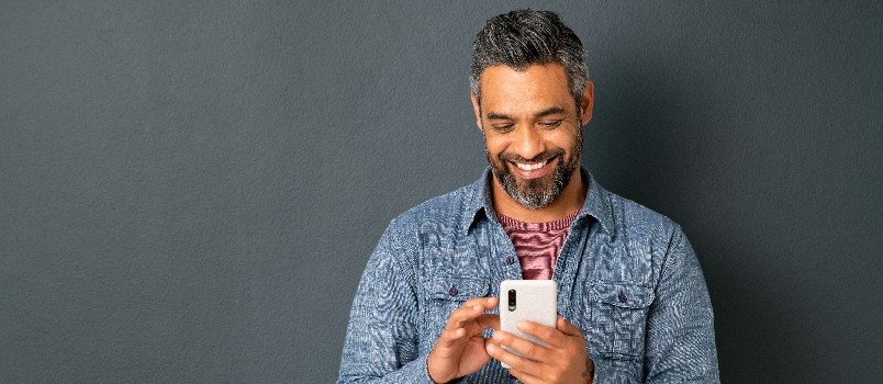 Hombre sonriendo mientras usa el teléfono inteligente