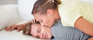 Mujer besando al hombre mientras duerme