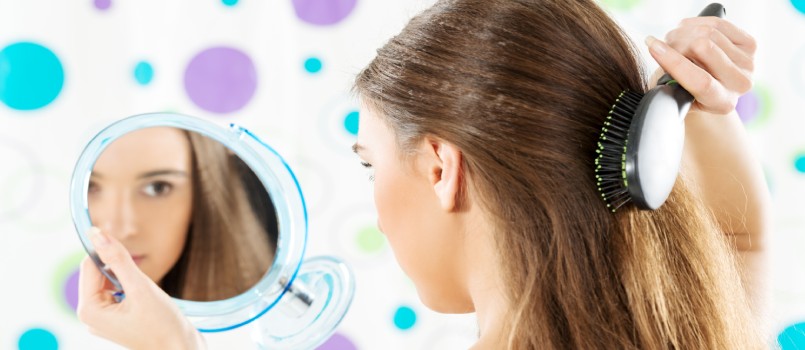 Chica mirándose en el espejo mientras se peina