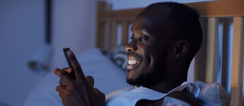 Hombre africano sonriendo mientras mira el teléfono