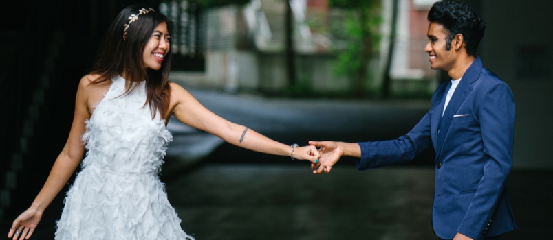 Una pareja interracial recién comprometida toma sus fotografías previas a la boda durante el día en un parque