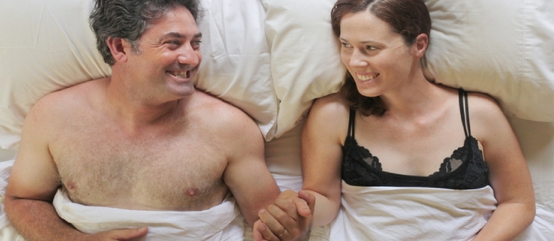 Vista superior de dos personas felices, un hombre y una mujer tomados de la mano yacían en la cama