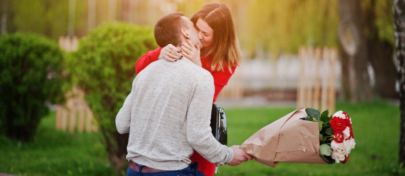 Feliz pareja romántica besándose en el parque y abrazándose juntos