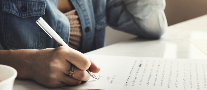 Mujer escribiendo una carta de amor en una página blanca