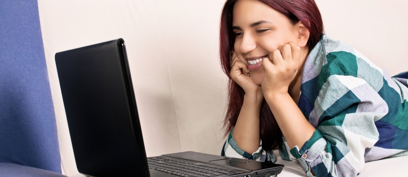 Señorita haciendo videollamada a través de una computadora portátil y sonriendo