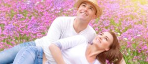 Feliz pareja pasando tiempo al aire libre, acostada y abrazándose en un hermoso campo floral rosa, relación romántica, concepto de amor
