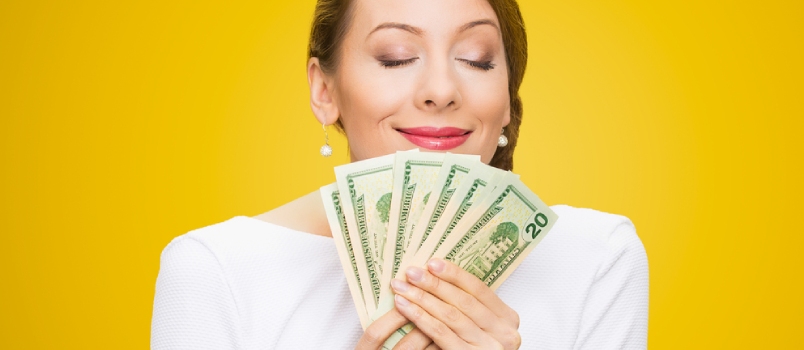 Una mujer sosteniendo billetes de dólar oliendo bien aislado fondo amarillo
