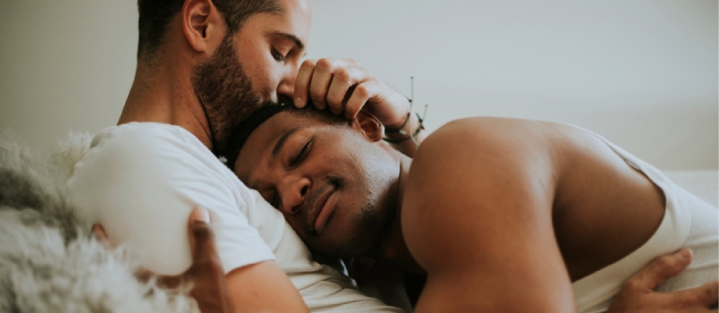 Pareja gay abrazándose en la cama
