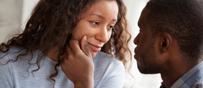 Amoroso hombre afroamericano animando a su amada mujer tocando su rostro relajándose juntos en casa