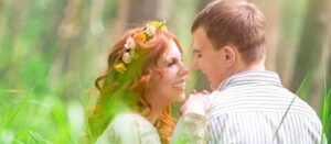 Hermosa novia y novio guapo sentados en la hierba verde fresca y hablando, amor y felicidad en el día de la boda