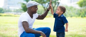 Padre moderno dando un saludo a su pequeño hijo en el parque