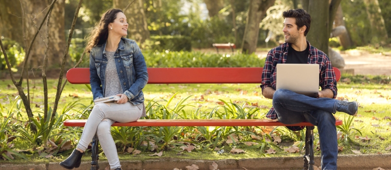 Dos amigos conociéndose sentados en el banco del parque