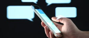 Fondo de símbolos de mensajes negros con mensajes de texto de mano cercana sobre una toma de teléfono móvil