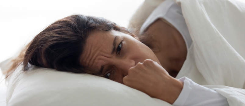 Una mujer deprimida de cerca acostada sobre una almohada en la cama se siente infeliz por las relaciones arruinadas, el divorcio y la ruptura con un ser querido