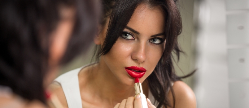 Hermosa mujer aplicando lápiz labial rojo
